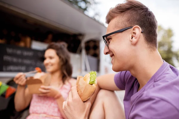 Hombre feliz comiendo hamburguesa en camión de comida — Foto de Stock