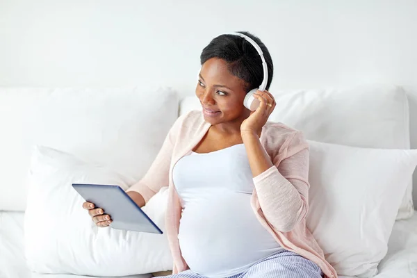 Schwangere im Kopfhörer mit Tablet-PC — Stockfoto