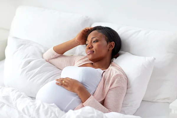 Kobieta w ciąży leżąc w łóżku w domu — Zdjęcie stockowe