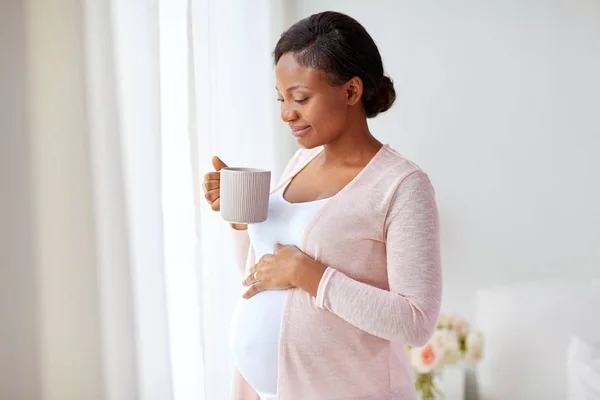 Mujer embarazada feliz con taza de té en casa —  Fotos de Stock