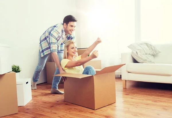 Feliz pareja divirtiéndose con cajas en nuevo hogar — Foto de Stock