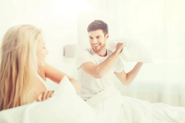 Couple heureux ayant bataille d'oreillers dans le lit à la maison — Photo