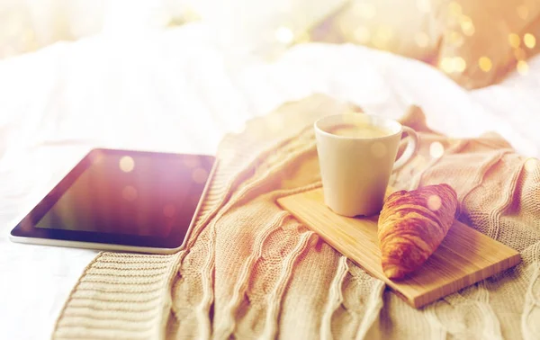Tablet pc, kahve ve kruvasan evde yatakta — Stok fotoğraf