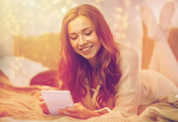 Happy young woman with notebook in bed at home — Stock Photo, Image