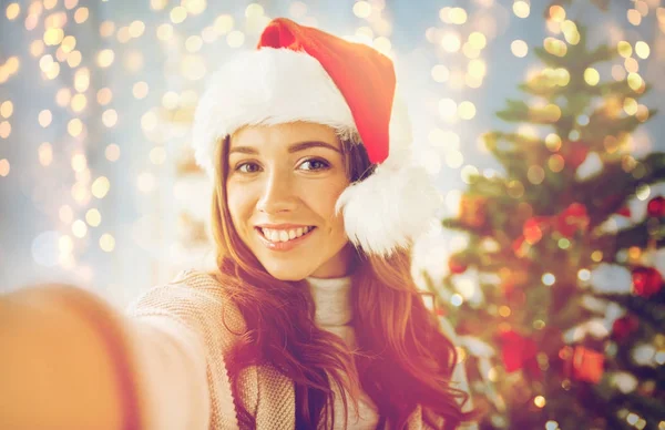 Mulher feliz em santa chapéu sobre árvore de natal — Fotografia de Stock