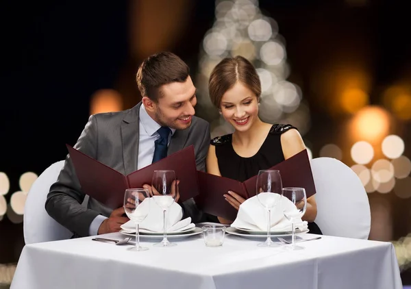 Улыбающаяся пара с меню в рождественском ресторане — стоковое фото