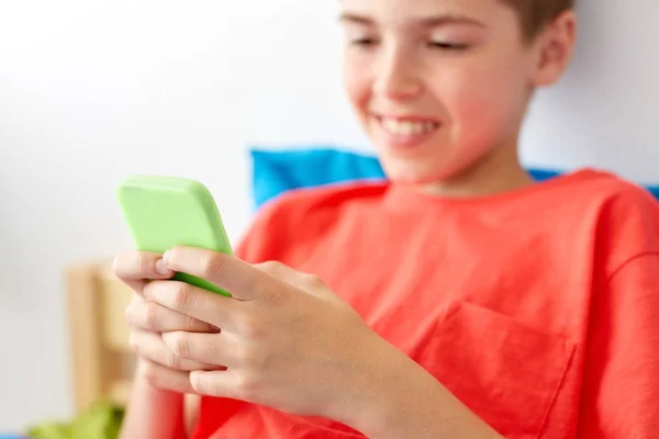 Primer plano de niño feliz con teléfono inteligente en casa — Foto de Stock