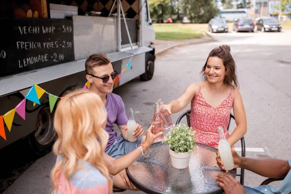 Amici clinking bottiglie con bevande al camion cibo — Foto Stock