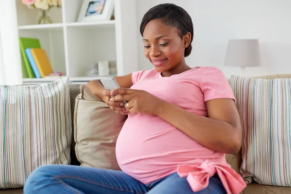 Femme enceinte heureuse avec smartphone à la maison — Photo