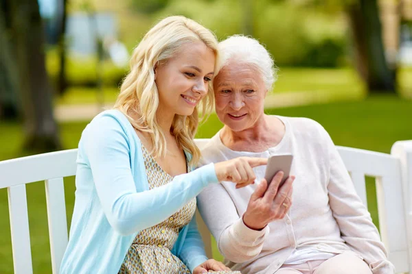 Dochter en senior moeder met smartphone bij park — Stockfoto