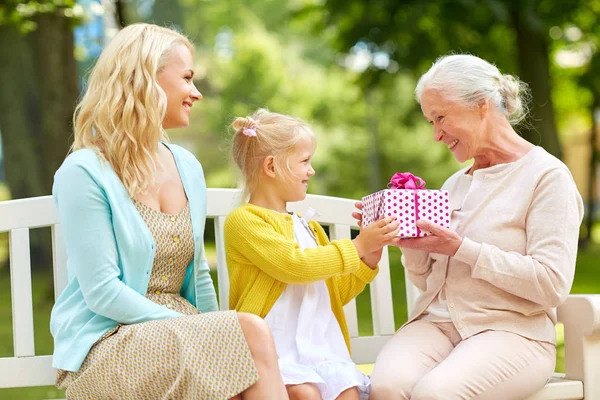 Feliz familia dando regalo a la abuela en el parque — Foto de Stock