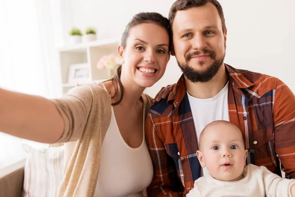 Ibu dan ayah dengan bayi mengambil selfie di rumah — Stok Foto