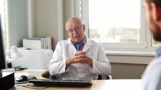 Старший лікар розмовляє з пацієнтом чоловічої статі в лікарні — стокове відео