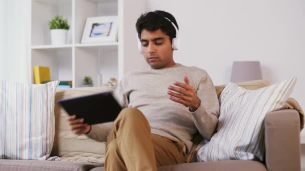 Hombre con tablet PC y auriculares en casa — Vídeos de Stock