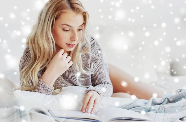 Young woman reading book in bed at home — Stock Photo, Image