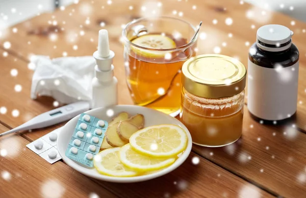 Medicamentos, termómetro, miel y taza de té sobre madera Imágenes de stock libres de derechos