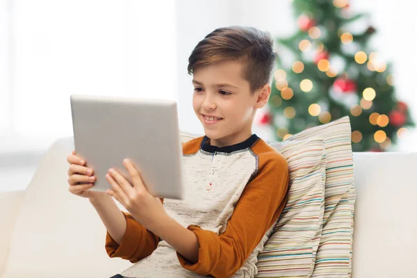 Улыбающийся мальчик с планшетным ПК дома на Рождество — стоковое фото