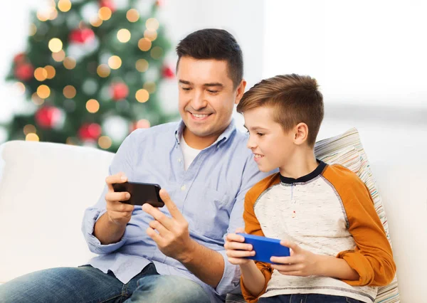 Feliz padre e hijo con teléfonos inteligentes en Navidad — Foto de Stock