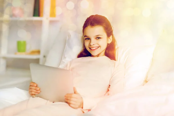 Chica feliz acostada en la cama con la tableta PC en casa —  Fotos de Stock