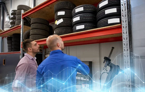 Mecánico y hombre la elección de neumáticos en el taller de automóviles —  Fotos de Stock