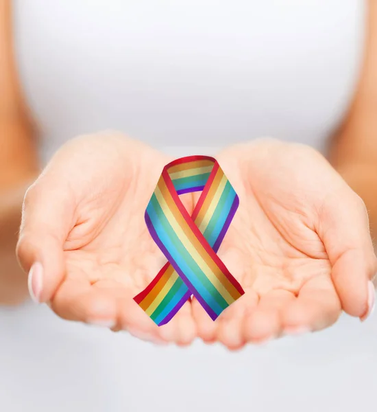 Kvinnliga händer som håller gay pride awareness ribbon — Stockfoto