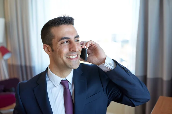 Hombre de negocios llamando en el teléfono inteligente en la habitación de hotel — Foto de Stock