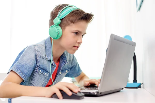 Jongen in hoofdtelefoon spelen video game op laptop — Stockfoto