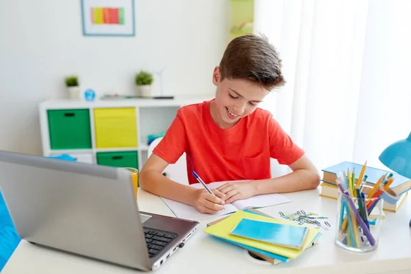 Student pojke med laptop skriva till anteckningsbok — Stockfoto
