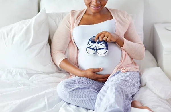 Mulher africana grávida com botas de bebê na cama — Fotografia de Stock