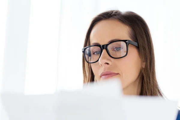 Mujer de negocios en gafas leyendo papeles en la oficina — Foto de Stock