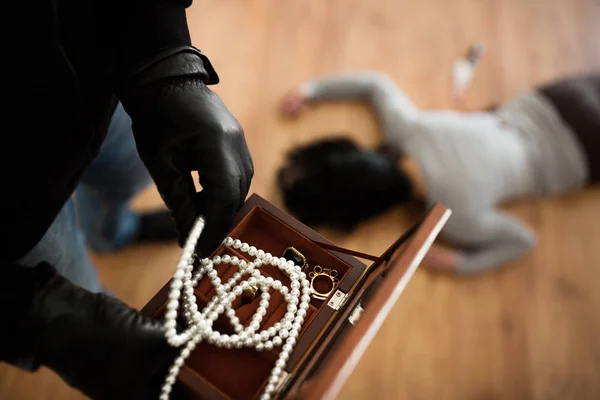 Criminal with knife and jewelry at crime scene — Stock Photo, Image