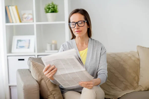 Mulher em óculos ler jornal em casa Imagem De Stock
