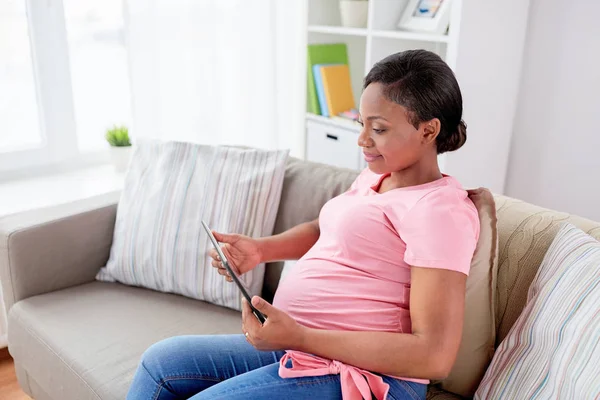 Ευτυχισμένη έγκυος γυναίκα με tablet pc στο σπίτι — Φωτογραφία Αρχείου