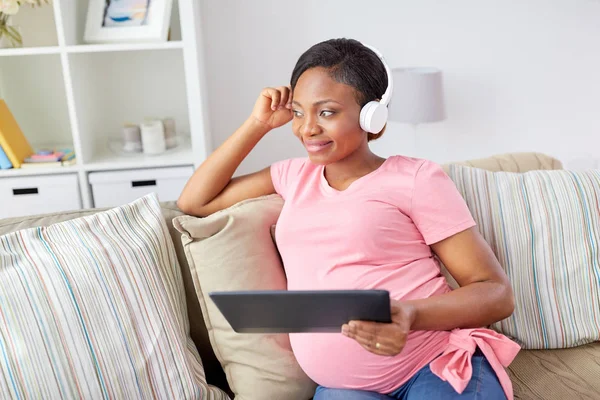 Femme enceinte dans un casque avec tablette pc — Photo