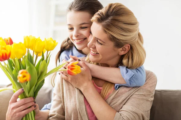 Glückliches Mädchen schenkt Mutter zu Hause Blumen — Stockfoto