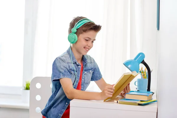 Studente ragazzo in cuffia lettura libro a casa — Foto Stock