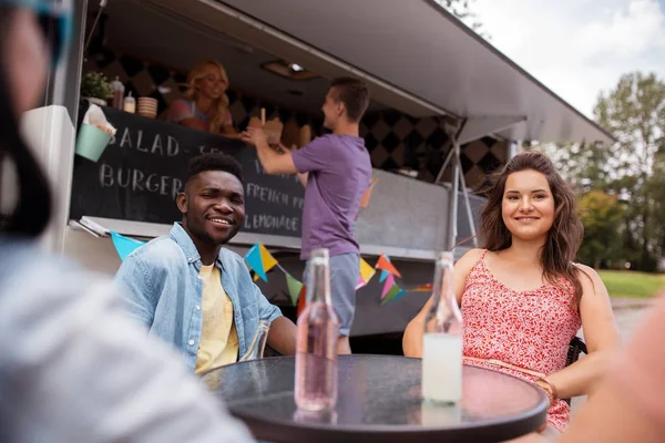 Vänner med drycker som sitter vid bord på foodtruck — Stockfoto