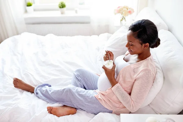 Kobieta w ciąży, jedzenie jogurt w łóżku — Zdjęcie stockowe