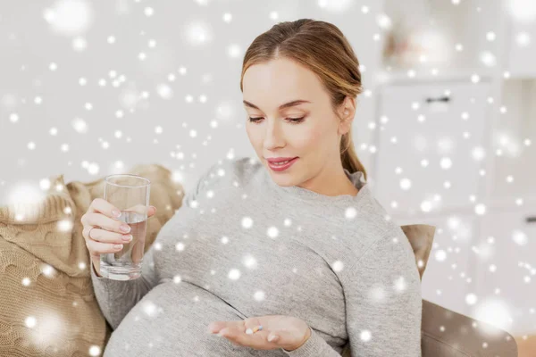 Gelukkig zwangere vrouw met water en pillen thuis — Stockfoto