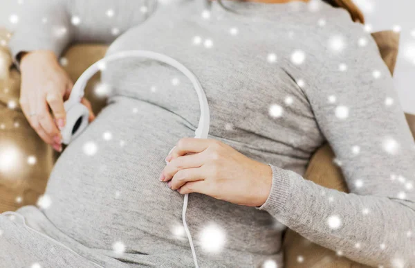 Беременная женщина с наушниками, слушающая музыку — стоковое фото