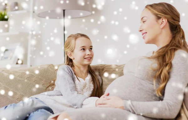 Feliz mujer embarazada y chica en el sofá en casa — Foto de Stock