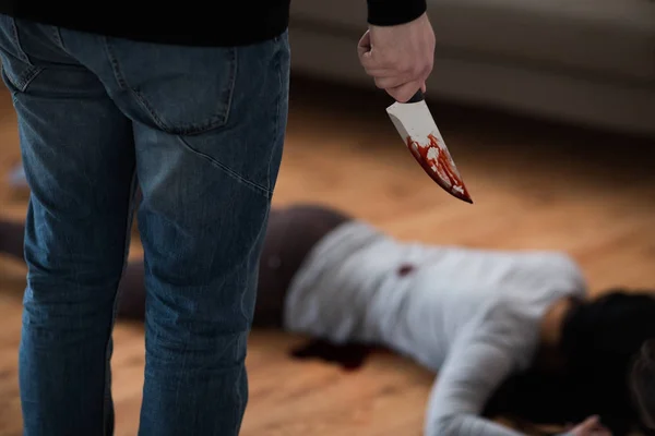 Criminal with knife and dead body at crime scene — Stock Photo, Image