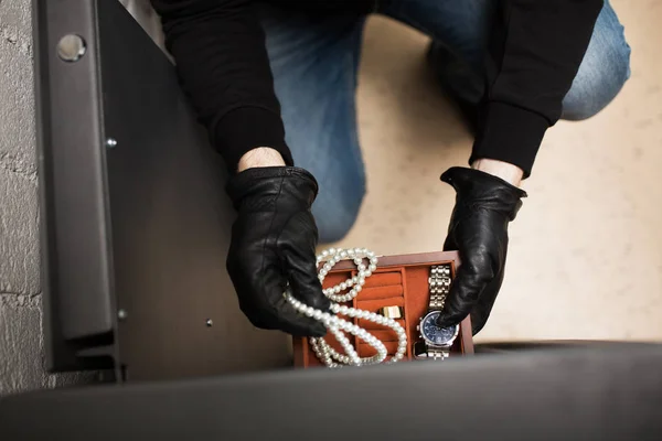 Voleur volant des objets de valeur dans un coffre-fort sur les lieux du crime — Photo