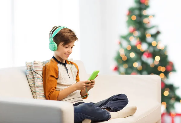 Niño con smartphone y auriculares en Navidad —  Fotos de Stock