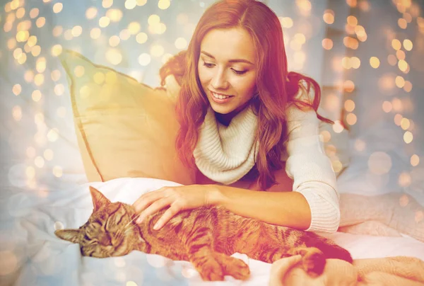 Jovem feliz com gato deitado na cama em casa — Fotografia de Stock