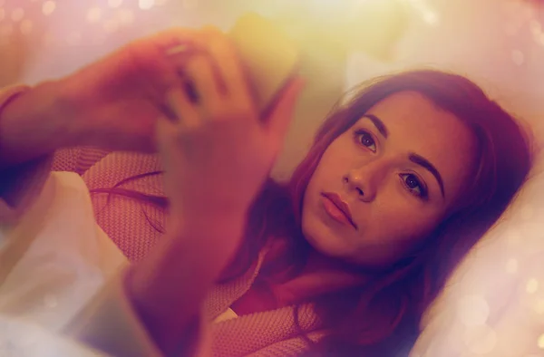 Genç kadın ile smartphone ev yatak odası, yatakta — Stok fotoğraf