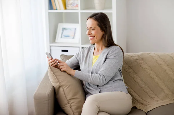 Happy woman texting message on smartphone at home — Stock Photo, Image