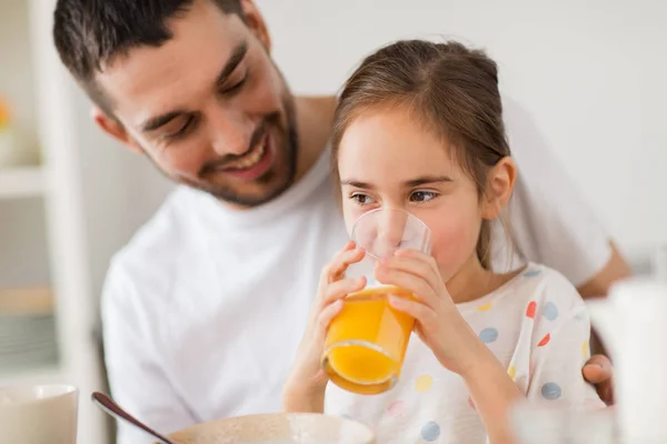 Счастливая девочка с отцом пьют сок дома — стоковое фото