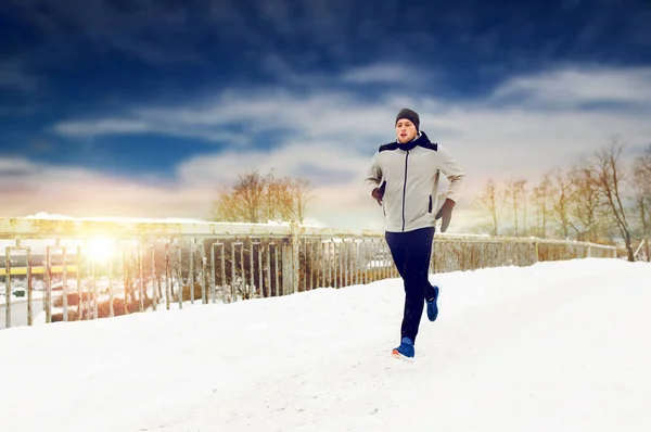 Человек бежит по заснеженной дороге зимнего моста — стоковое фото