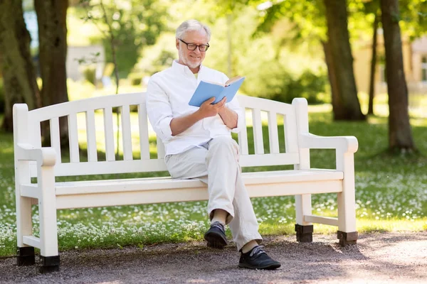 Gelukkig senior man leesboek in zomer park — Stockfoto